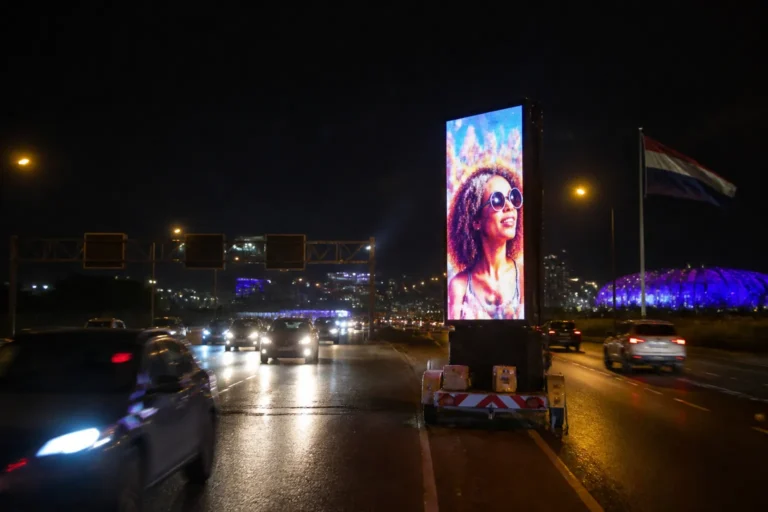 mobiel led-billboard op trailer langs drukke snelweg bij Nederlands verkeersknooppunt in de schemering